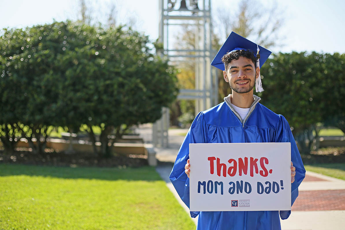 Graduate holding sign thanking mom and dad